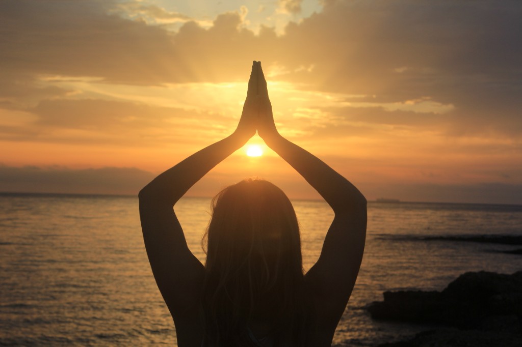 Sunset over the sea, hands in prayer